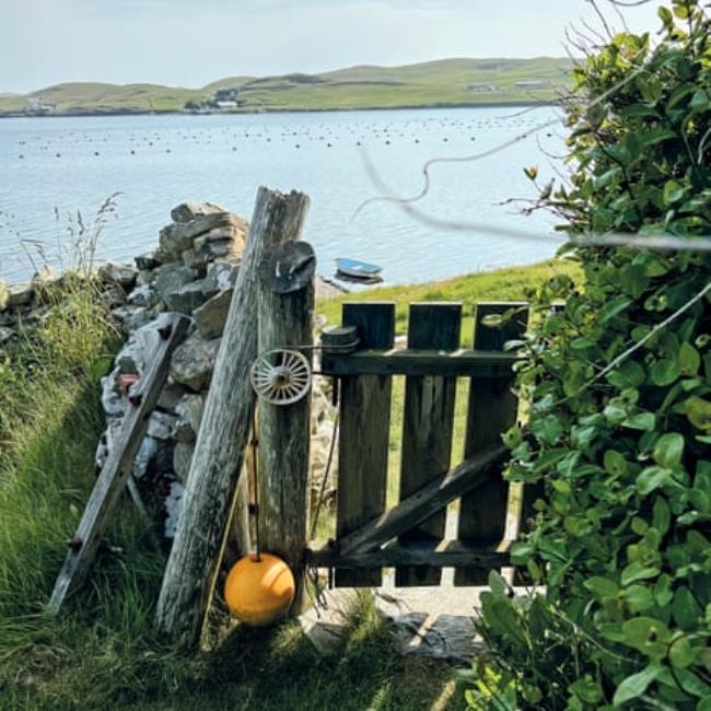 View over a garden gate hung with a buoy looking out to sea